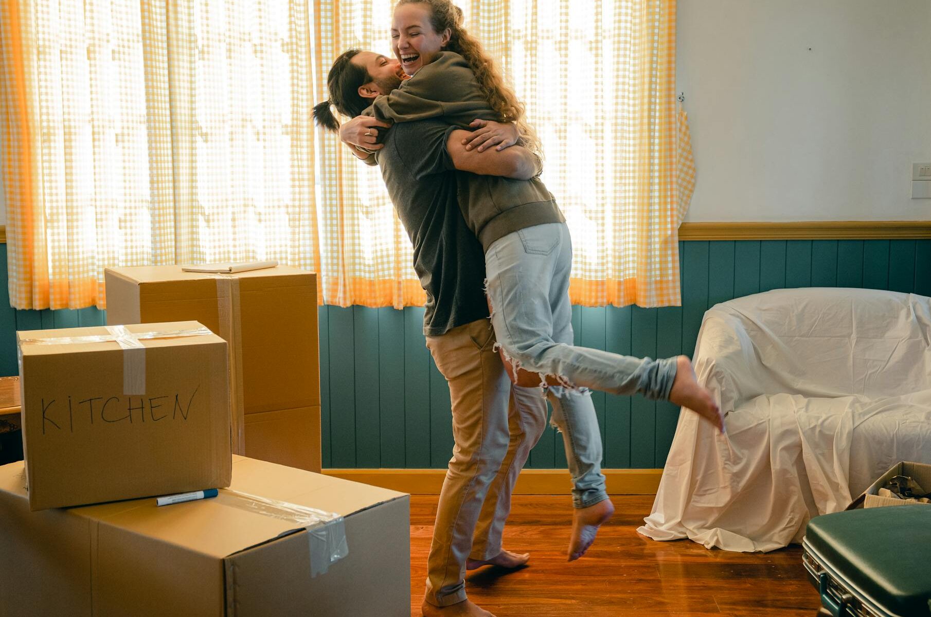 cheerful couple hugging and unpacking carton boxes